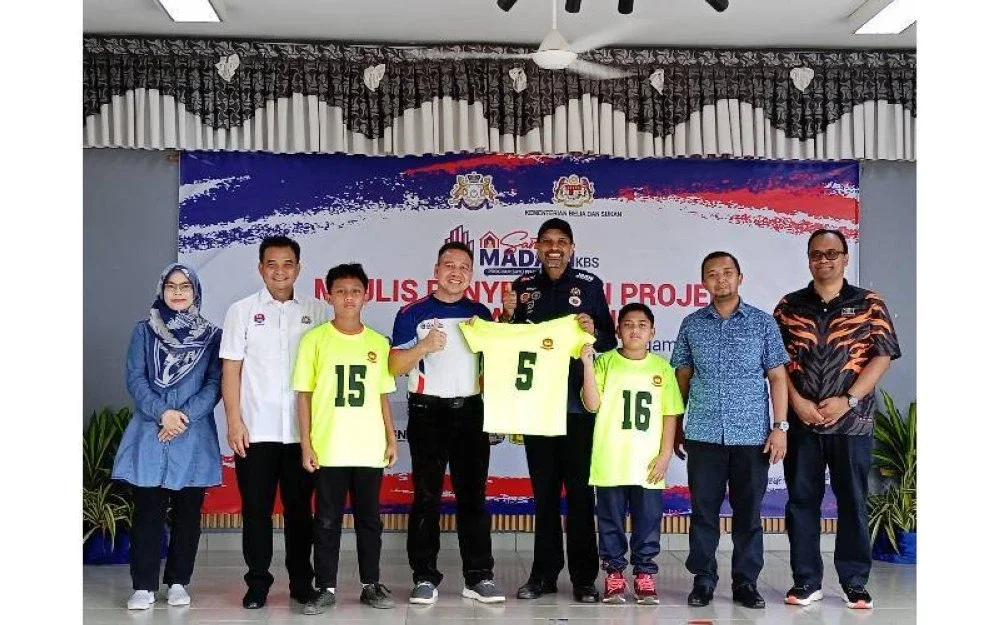 Nagulendran (empat kanan) menyerahkan jersi kepada Guru Besar SK Spang Loi, Abd Aziz Daud selepas penyerahan Program Santuni MADANI, pada Sabtu.