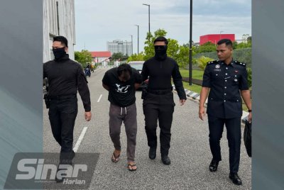 Ramizu (dua dari kiri) dikawal polis ketika tiba di Mahkamah Sesyen Kota Bharu pada Isnin.