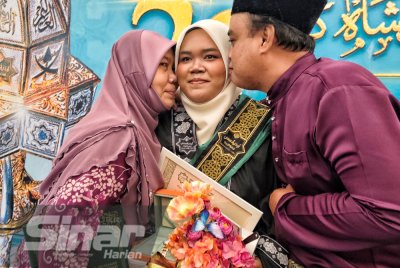 Siti Nur Khalidah (tengah) menerima kucupan daripada ibu dan bapanya selepas menerima Anugerah Sultan Ahmad Shah pada Istiadat Konvokesyen Ke-22, UniPSAS di Dewan Jubli Perak Sultan Haji Ahmad Shah, Kuantan pada Isnin.