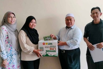 Ahmad Mustaqim menyampaikan sumbangan kepada Madihah Izzati Atiqah sambil disaksikan Natipah (kiri).