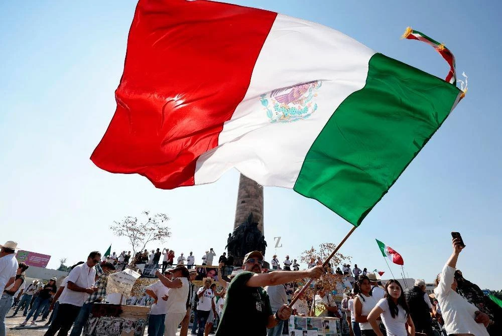 Seorang lelaki mengibarkan bendera Mexico semasa protes berkenaan.