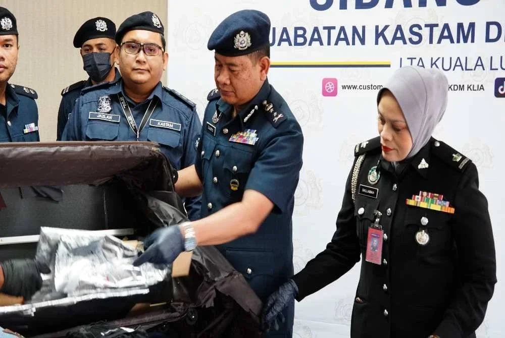 Zulkifli (dua dari kanan) menunjukkan dadah yang ditemui dalam bagasi dirampas.