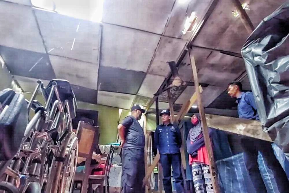 Asmadi melihat keadaan rumah Roslina yang rosak akibat ribut di Bukit Bay Route.