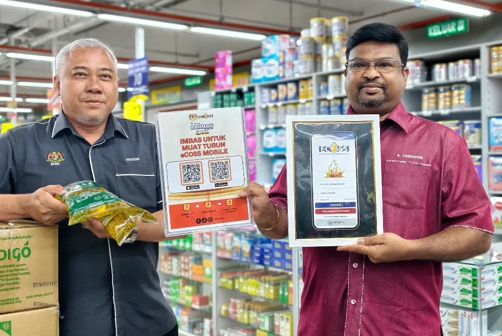 Veerapan (kanan) menunjukkan aplikasi eCOSS yang perlu dimuat turun pengguna bagi tujuan membeli minyak masak peket bersubsidi.