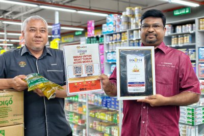 Veerapan (kanan) menunjukkan aplikasi eCOSS yang perlu dimuat turun pengguna bagi tujuan membeli minyak masak peket bersubsidi.