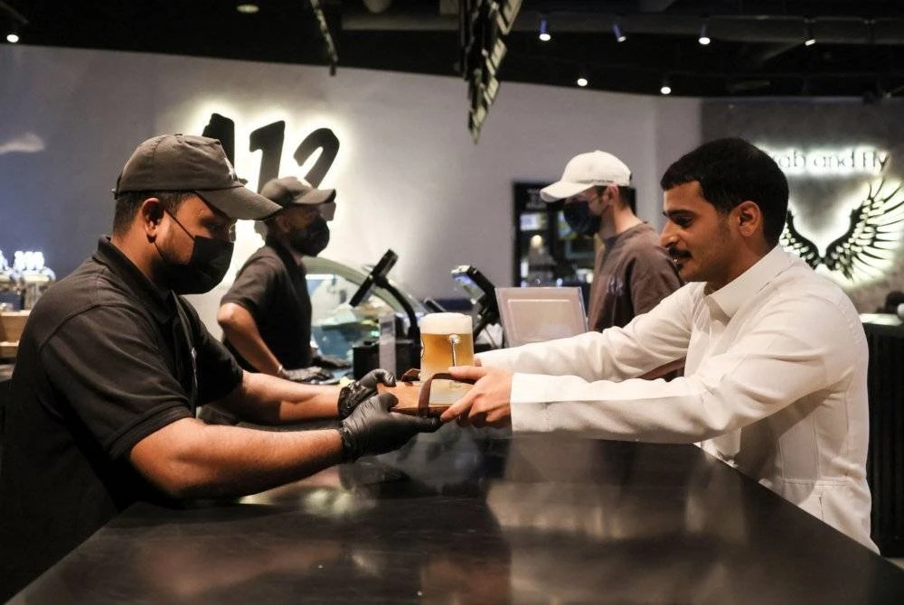 Seorang pelayan bar menyajikan bir tanpa alkohol kepada seorang pelanggan Saudi di kafe A12.