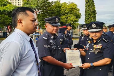 Mohd Yusoff (kanan) menyampaikan sijil penghargaan pada Perhimpunan Bulanan Polis di Ibu Pejabat Polis Kontinjen (IPK) Kelantan di Kota Bharu pada Rabu.