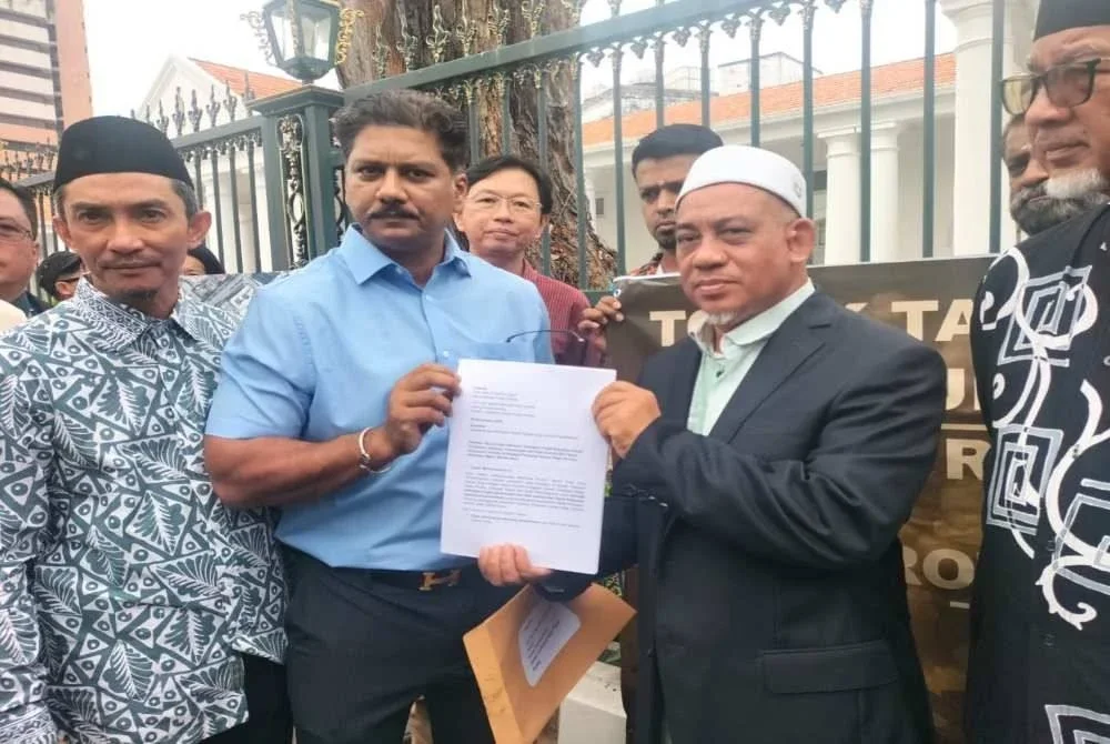 Ganesh (dua dari kiri) menyerahkan memorandum mendesak penolakkan kerja penambakan dan kerja kitar semula kepada Muhammad Fauzi di hadapan bangunan Dewan Undangan Negeri Pulau Pinang pada Khamis.