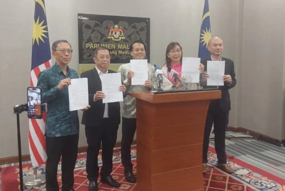 Nik Nazmi (tengah) menunjukkan draf RUU untuk pindaan Akta 190 bersama Ahli Parlimen Kuala Lumpur dalam sidang akhbar di Dewan Rakyat pada Khamis.