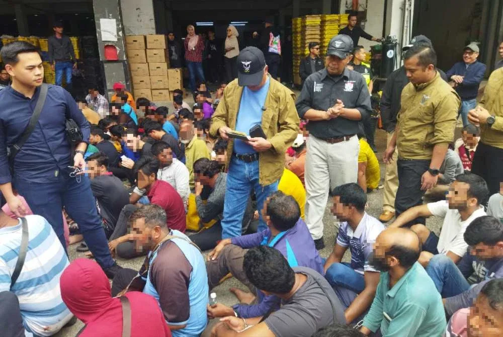 Zakaria (dua dari kiri) melihat pasport milik warga asing dalam Ops Gempur di sini pada Khamis.