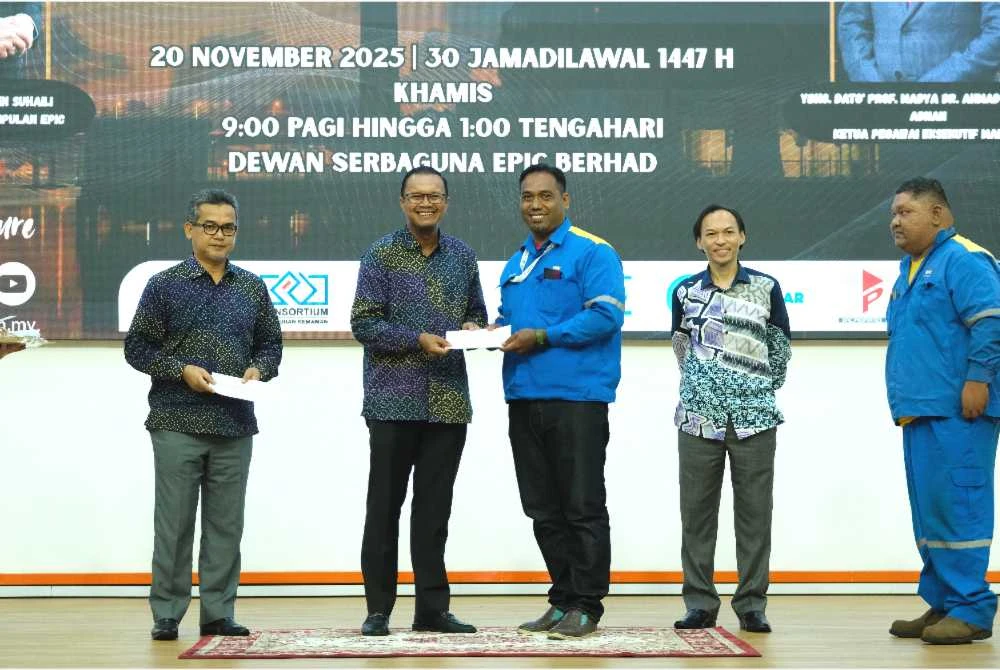 Azrin (dua kanan) menyaksikan penyerahan zakat disampaikan oleh Muhtar kepada penerima sempena program diadakan di Dewan Serbaguna EPIC Berhad di Kemaman pada Khamis.