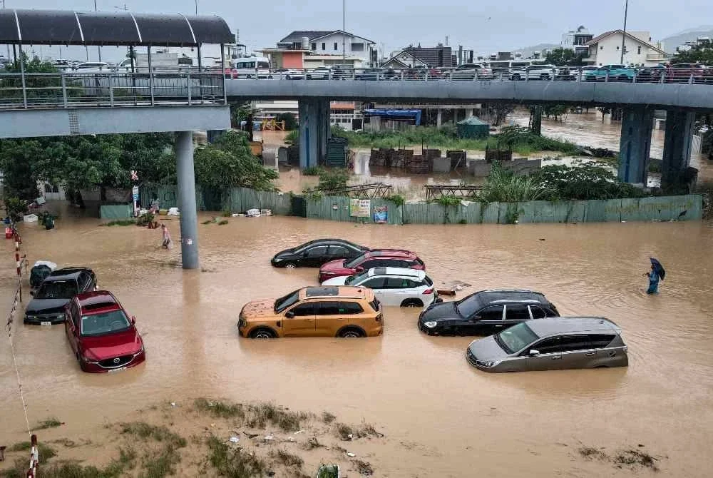 Seorang lelaki menempuh air banjir berhampiran kenderaan yang tenggelam di Nha Trang, wilayah pesisir Khanh Hoa, Vietnam. Foto: AFP