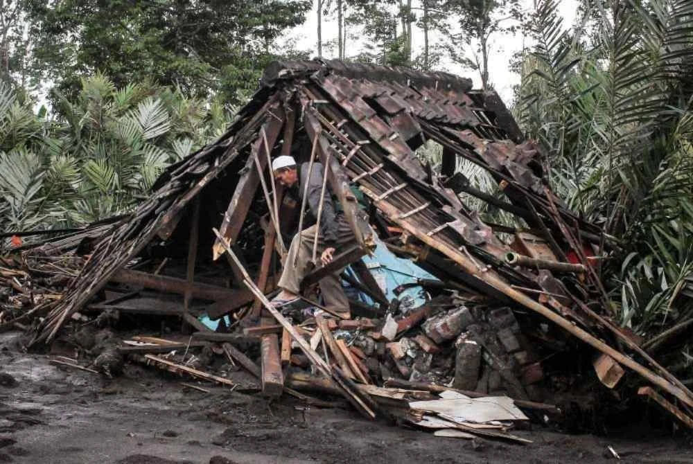 Seorang lelaki mencari barangan untuk diselamatkan di dalam rumahnya yang musnah akibat aliran lava panas selepas letusan Gunung Semeru di kampung Supiturang, Lumajang.