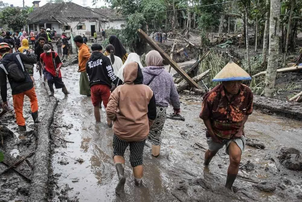 Orang ramai berjalan di atas laluan yang dilitupi lumpur abu letusan Gunung Semeru.
