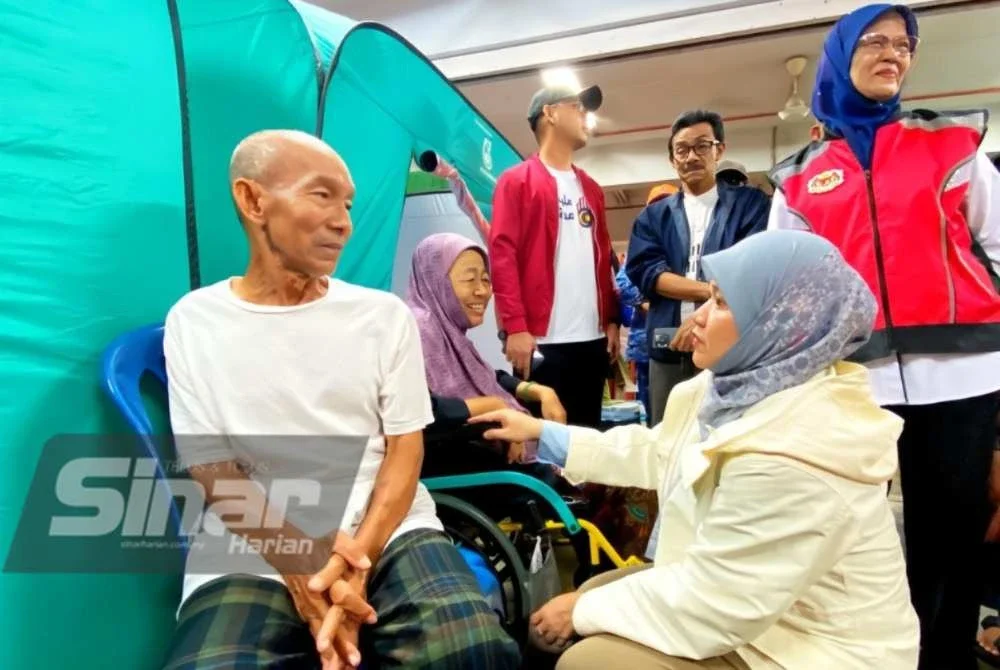 Fadhlina (kanan) bertanyakan khabar mangsa banjir melakukan tinjauan di PPS SK Tapang, Kota Bharu pada Ahad.