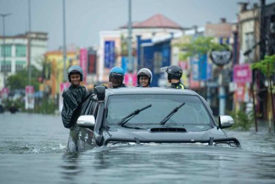 Penduduk dan kenderaan terjejas susulan air naik di Taman Bendahara, Pengkalan Chepa, akibat hujan lebat berterusan. Foto Bernama