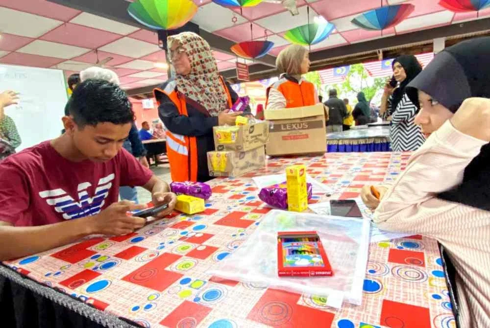 Nik Mohd Idham (kiri) terpaksa mengulangkaji melalui telefon apabila terpaksa meninggalkan buku, kelengkapan peperiksaan di rumah untuk menyelamatkan diri ke PPS SK Tapang, Kota Bharu selepas air naik terlalu cepat sehingga mencecah 0.6 meter pada Sabtu.