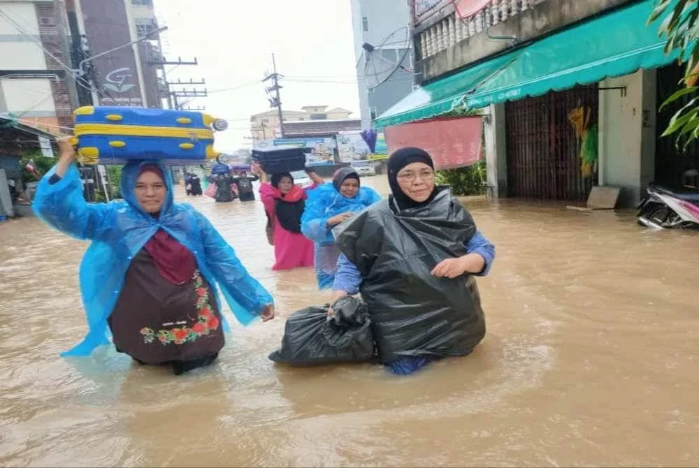 Maziah bersama ahli rombongan nekad meredah banjir sambil menjinjit beg pakaian masing-masing sejauh hampir satu kilometer.