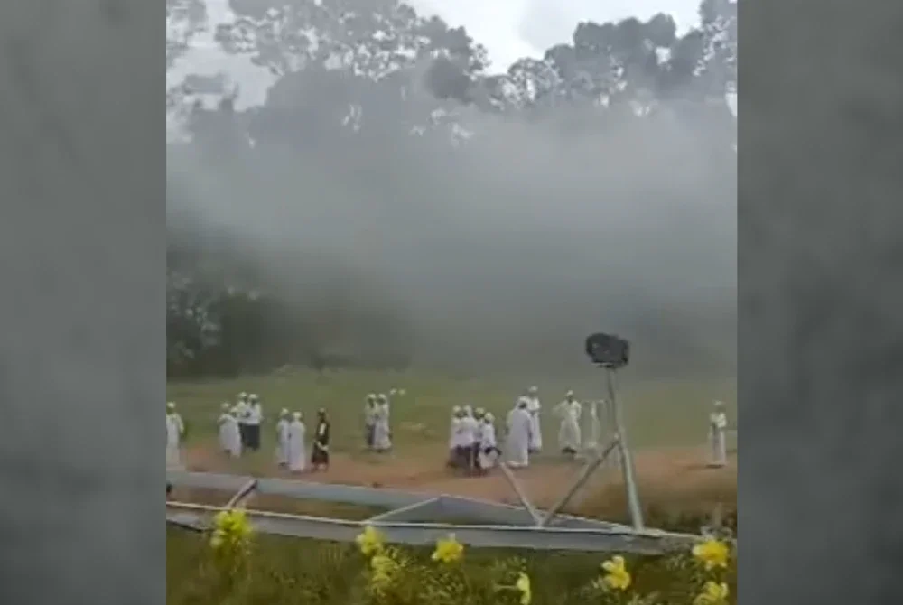 Pelajar tahfiz berkumpul di kawasan lapang di hadapan pusat tahfiz yang terbakar. - Foto tular