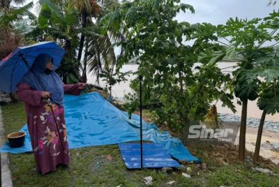 Harniza menunjukkan keadaan tanah runtuh di belakang rumahnya. Foto: ADILA SHARINNI WAHID