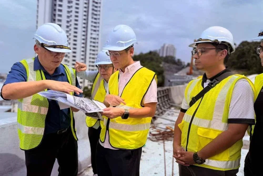 Zairil (dua dari kanan) mendengar taklimat daripada pekerja tapak mengenai pemasangan rasuk di Projek Pakej 2: Jalan Pintasan dari Lebuhraya Tun Dr Lim Chong Eu ke Ayer Itam.