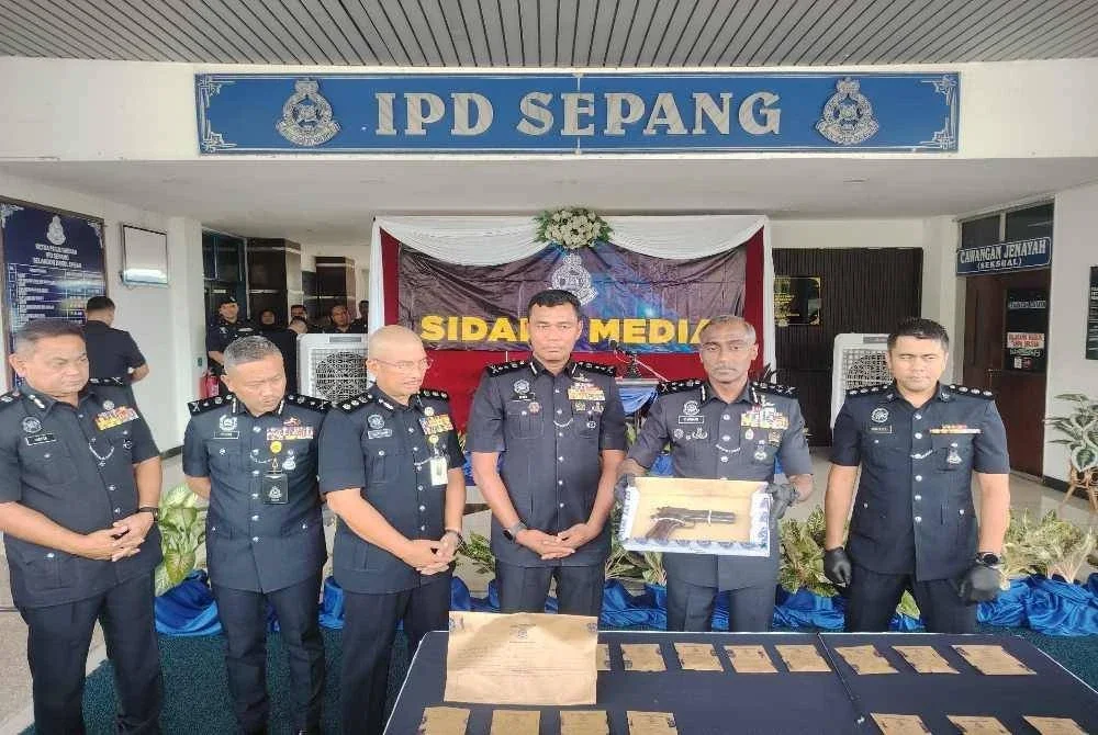 Kumar (dua dari kanan) menunjukkan pistol yang dirampas selepas kejadian berbalas tembakan suspek dengan pasukan polis di Jalan Banting - Dengkil, Sepang.