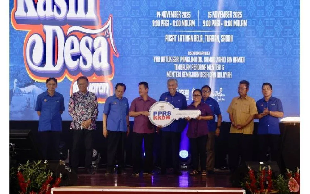 Timbalan Perdana Menteri, Datuk Seri Ahmad Zahid Hamidi ketika menyampaikan kunci kepada salah seorang penerima PPRS pada Program Sentuhan Kasih Desa @ Tuaran di Pusat Latihan RELA Tuaran, baru-baru ini.