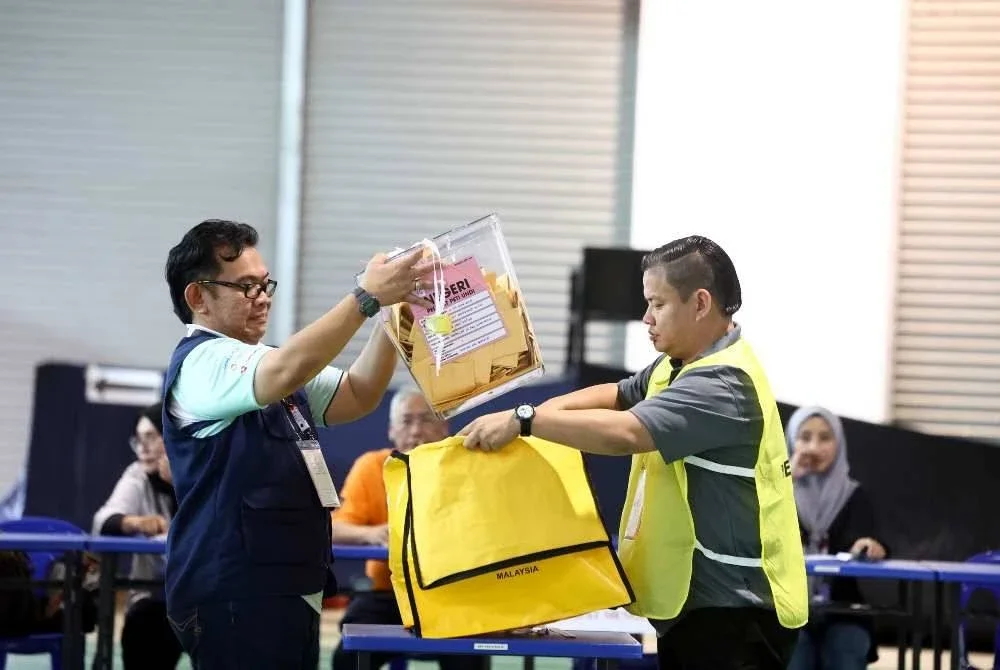 Ketua tempat mengundi, Supian Basrih (kiri), mengunci peti undi selepas pusat pengundian awal ditutup tepat jam 5 petang di Blok Serbaguna 15 Batalion, 15 PGA Sandakan pada Selasa. Foto: Bernama