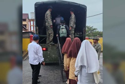 Calon SPM yang terjejas banjir dibawa menggunakan trak tentera. 