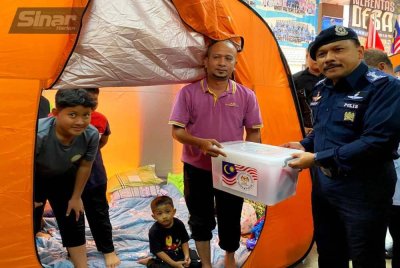 Mohd Yusoff (kanan) menyampaikan bantuan kepada penghuni PPS SK Kok Keli, Tumpat pada Selasa. 