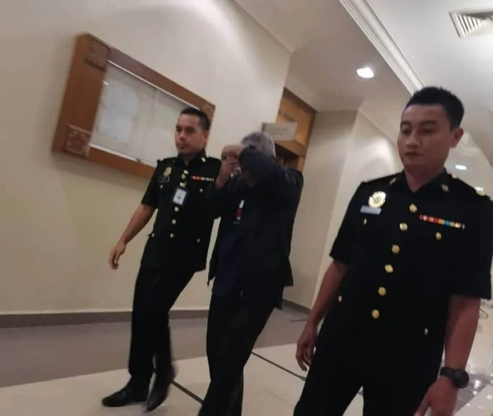 Tertuduh diiringi pegawai SPRM keluar dari mahkamah selepas sebutan kes selesai dibacakan pada Rabu.