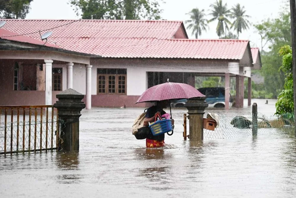 Seorang penduduk meredah banjir dari kediamannya menuju pusat pemindahan sementara (PPS) di Kampung Rawai, Marang. Foto Bernama