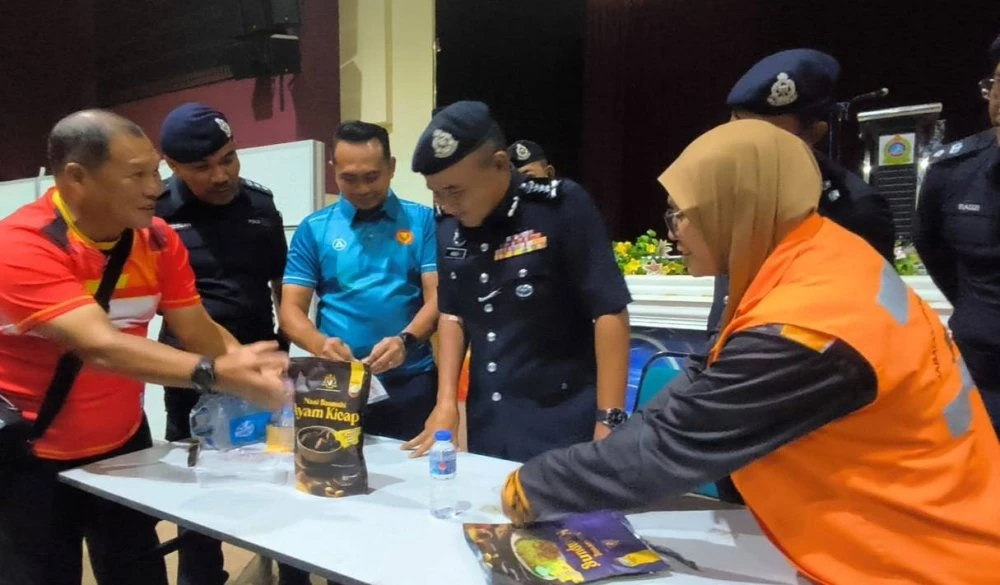 Adzli (dua dari kanan) melihat makanan yang dibekalkan kepada mangsa terjejas di PPS Dewan Wawasan Jitra, pada Rabu. 