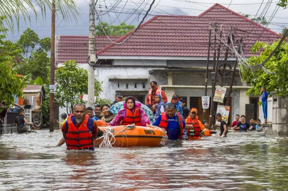 Pasukan penyelamat memindahkan wanita dan kanak-kanak menaiki bot getah ketika banjir melanda kawasan perumahan di Padang, Sumatera Barat. Foto AFP