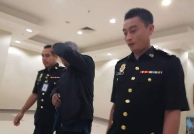 Tertuduh diiringi pegawai SPRM keluar dari mahkamah selepas sebutan kes selesai dibacakan pada Rabu.