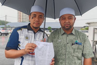 Muhammad Hamdi (kanan) dan Irsyad Syafiq menunjukkan laporan polis dibuat di IPD Kuala Terengganu pada Rabu.