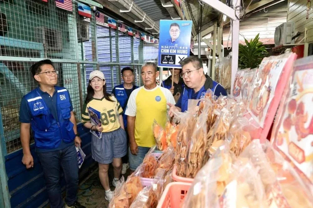 Kim Hiung (kanan) mendengar masalah peniaga di Kampung Pukat ketika beliau menjalankan kempen di kawasan itu.