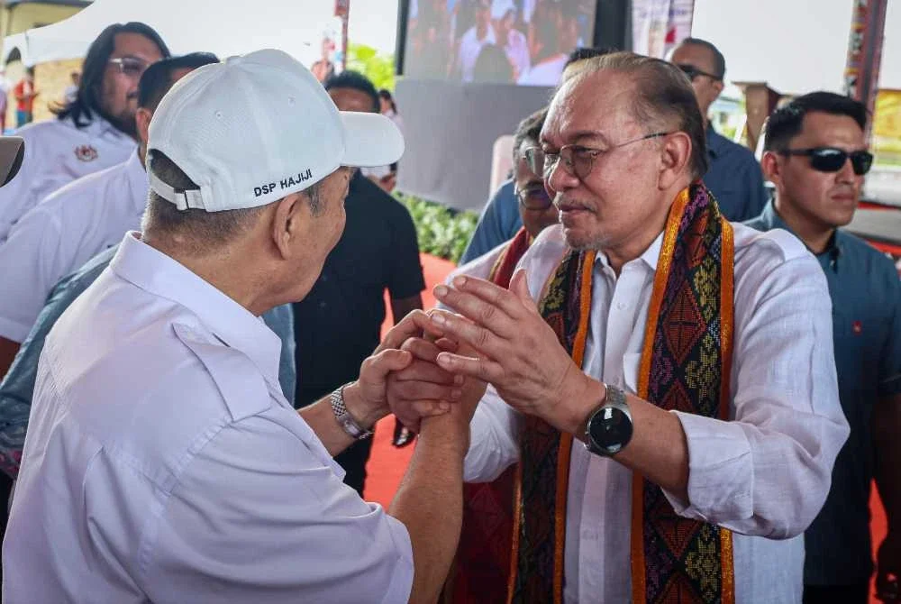 Anwar bersalaman dengan Hajiji Noor ketika temu rapat dengan pemimpin masyarakat tempatan dan sahabat usahawan Tuaran di Dewan Kebudayaan Bajau Samah, Sulaman hari ini. - Foto: Bernama