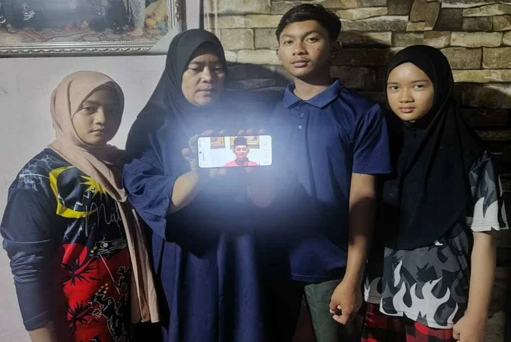 Rafidah (dua kiri) dan anak-anaknya menunjukkan gambar Allahyarham Fatah Ariffin yang meninggal dunia akibat serangan jantung pada 11 November lalu.
