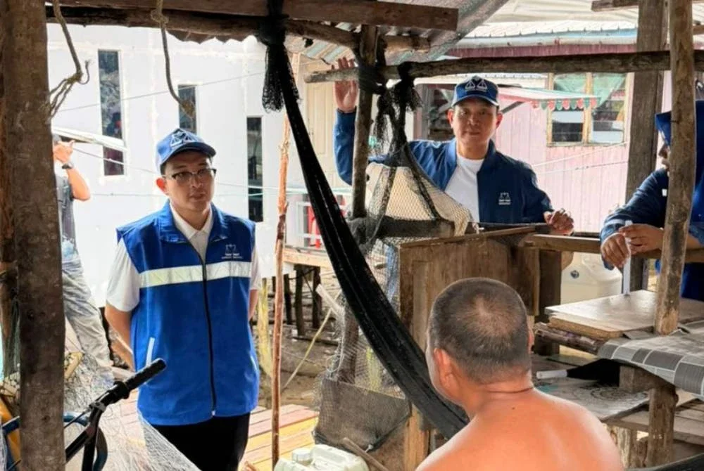 Shahnon Rizal (kiri) menyantuni pengundi-pengundi di Kampung Baru-Baru.