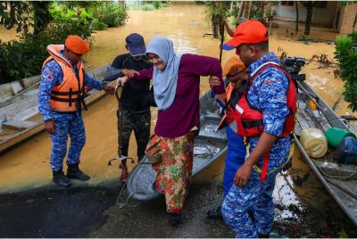 Anggota APM membantu memindahkan penduduk ke PPS SK Limau Kasturi berikutan kediaman mereka dilanda banjir semalam. - Foto: Bernama