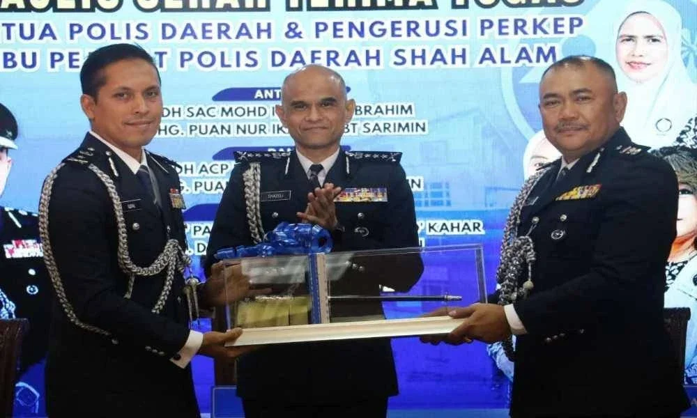Mohd Iqbal (kiri) menyerahkan simbolik tongkat kuasa kepada Ramsay sambil disamsikan Shazeli (tengah) ketika Majlis Serah Terima Tugas Ketua Polis Daerah Shah Alam pada Jumaat. 