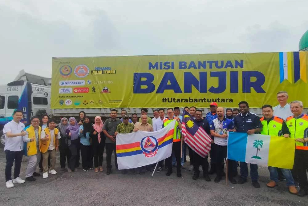 Lokman Hakim (tengah) bersama rakan NGO dan badan korporat bergambar bersama kontena yang akan menghantar barangan misi bantuan banjir ke Perlis, pada Jumaat.