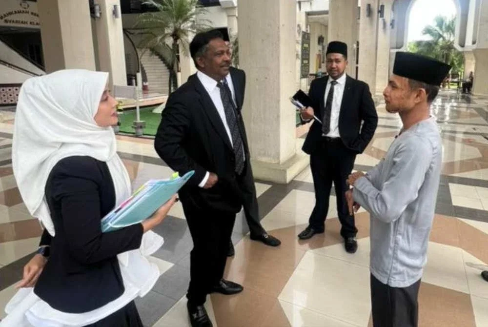 Faisal (kanan) berbincang dengan peguam-peguamnya di Mahkamah Rendah Syariah Klang pada Jumaat bagi pengesahan lafaz cerai terhadap isterinya.