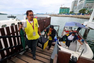 Petugas Suruhanjaya Pilihan Raya (SPR) membawa peti undi keluar dari Pulau Sepanggar menggunakan bot di Sabah Parks Jetty untuk dibawa ke pusat penjumlahan undi. - Foto Bernama
