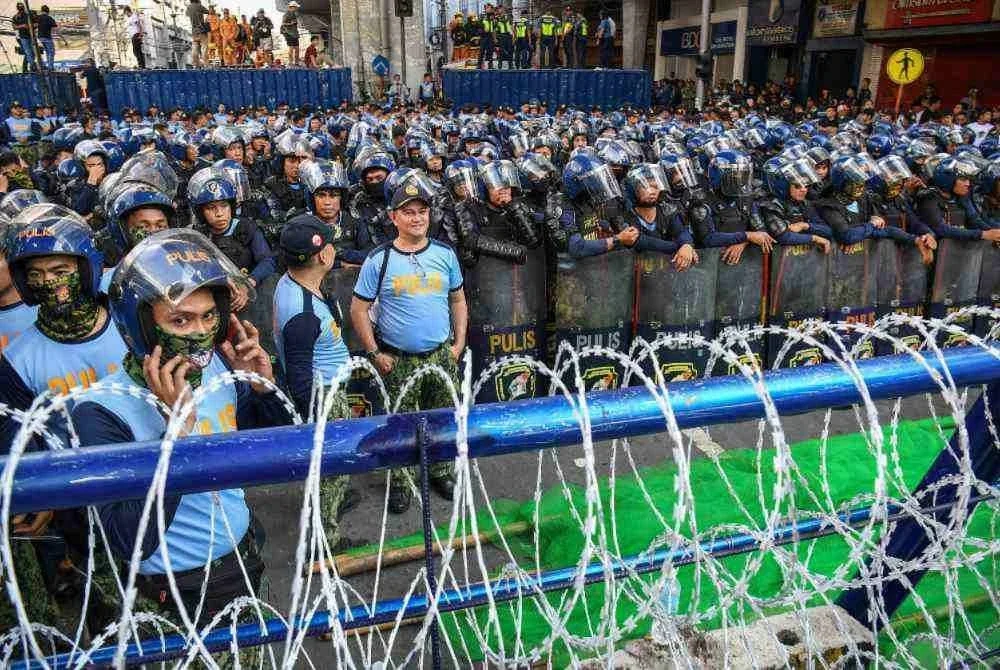 Pasukan polis anti rusuhan berdiri di belakang dawai berduri semasa perhimpunan antirasuah berhampiran Istana Malacanang di Manila. - Foto AFP