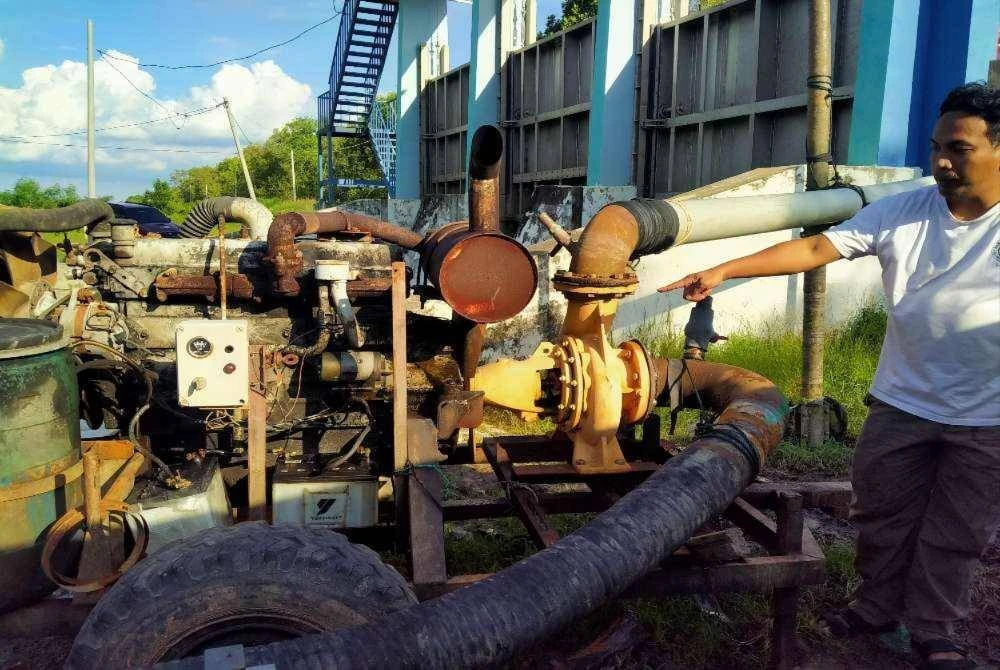 Muaz menunjukkan pam air yang digunakan untuk mengeluarkan air banjir ke laut berhampiran kunci air Parit 1 di sini pada Ahad.
