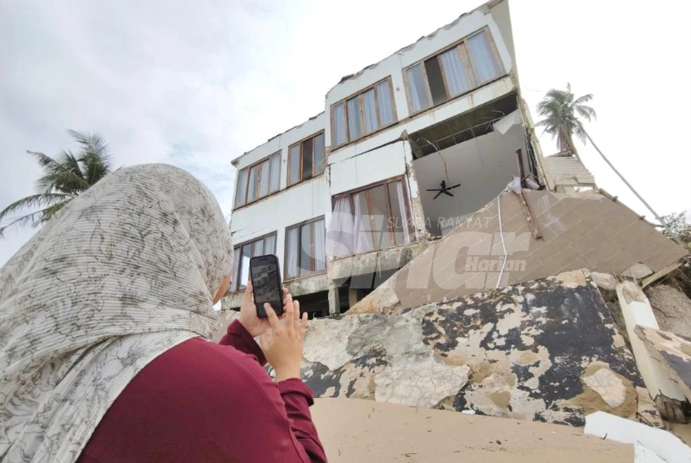 Penduduk setempat meninjau keadaan terkini vila putih yang menjadi tumpuan kerana hampir runtuh akibat fenomena hakisan pantai di Pantai Sauh, Kampung Mengabang Lekor, Batu Rakit di Kuala Nerus.