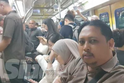 Wartawan Izwan Rozlin (kanan) meninjau kesesakan di dalam Monorel Kuala Lumpur pada waktu pagi.
