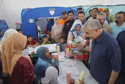 Ahmad Zahid menyantuni mangsa banjir yang ditempatkan di PPS dalam lawatannya meninjau keadaan banjir di Bagan Datuk, pada Isnin.
